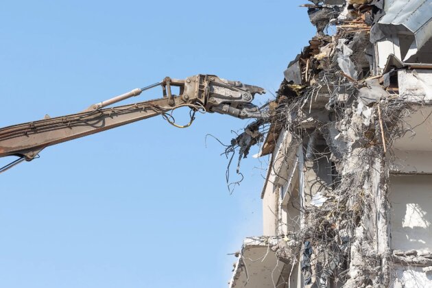 Heavy equipment hydraulic shears arrow dismantle the building, demolition destruction.